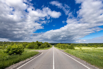 A long road with a clear blue sky and a few clouds