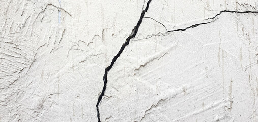 Cracked plaster. Damaged plastered, concrete wall in chips, cracks