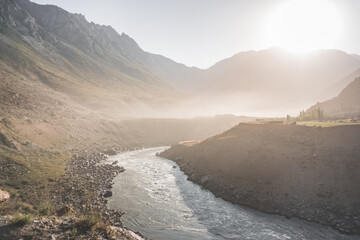 The powerful, stormy and noisy Panj River flows in a mountain valley along a dusty road of the Pamir Highway, the border of Tajikistan and Afghanistan, landscape in the Tien Shan Mountains