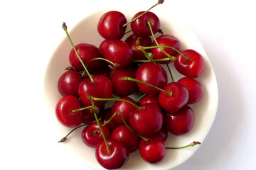 Fresh, delicious cherries in a white ceramic bowl on a white background