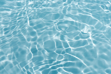 Blue water with ripples on the surface. Defocus blurred transparent blue colored clear calm water surface texture with splashes and bubbles. Water waves with shining pattern texture background.