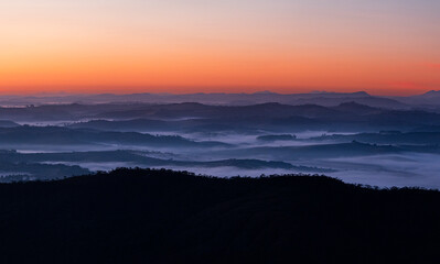 Paisagem do amanhecer com camandas de montanhas com nuvens baixas  e céu laranja