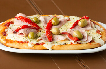 Argentinean pizza with ham, mozzarella, bell peppers and green olives