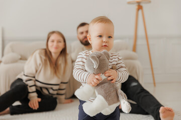 Laughter fills room as toddler enjoys floor play with his parents and toy, creating joyful and...
