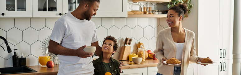 A man and a woman, a loving African American family with son, standing together in a kitchen.