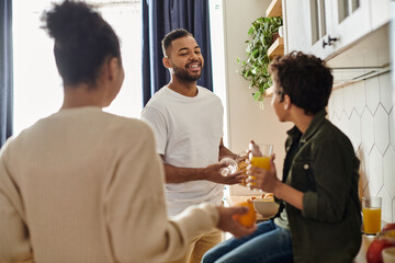 African American family stand around a kitchen, laughing and enjoying each others company.
