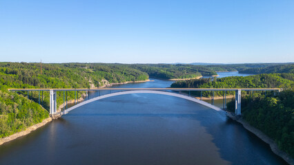 Fototapeta premium The Zdakov Bridge in the Czech Republic is a modern arch bridge over the Vltava River, offering a clear view of the surrounding countryside.