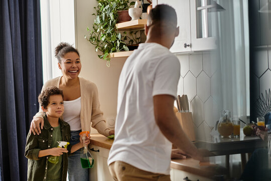 A man, woman, and young boy standing together in a home kitchen.