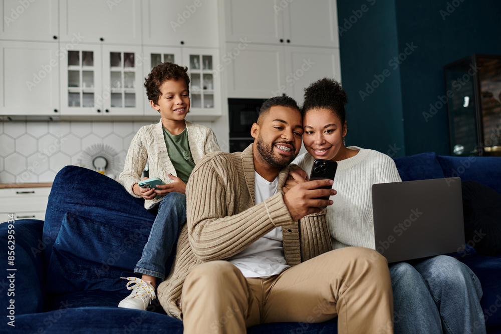 Wall mural african american family engrossed in a cell phone while sitting on a couch.