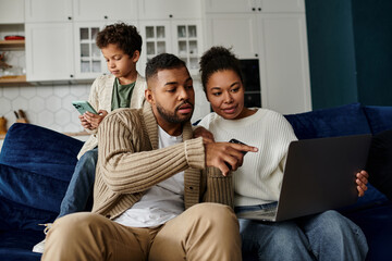 African american family engage with a laptop while seated on a couch.