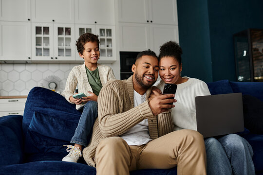 African american family engrossed in a cell phone while sitting on a couch.