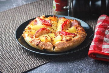 Pizza with crab sticks and cheese served on a restaurant table. With pepper and ketchup