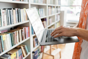 A student engrossed in studies, using a laptop in a library.