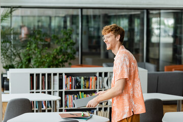 A man stands before a table with a laptop, immersed in his work.