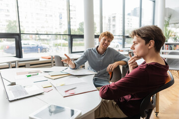 Two men engrossed in a business meeting at a table in a modern office setting.