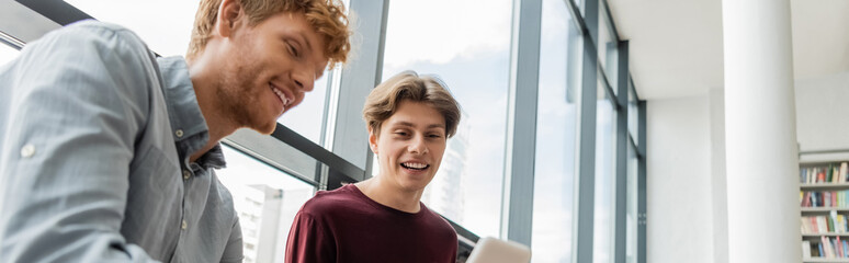 Two young men engrossed in a laptop at the library.
