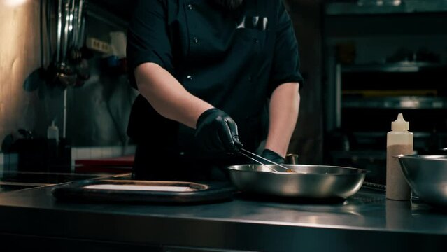 in a professional kitchen the chef puts ready-made chicken wings on wooden tray