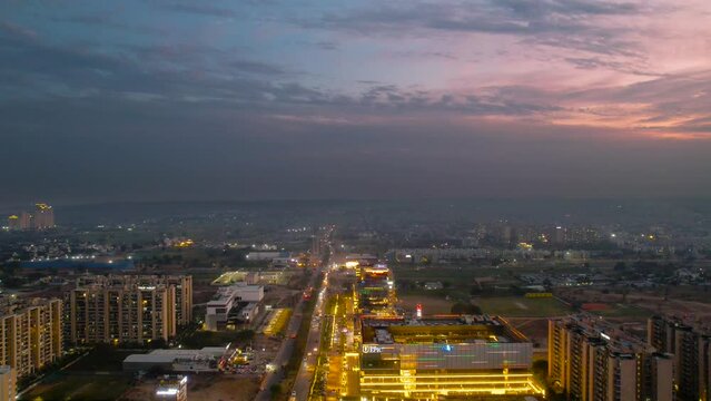 hyperlapse timelapse aerial drone shot showing fast moving traffic on long elevated highway passing between skyscrapers and smaller roads at dusk in gurgaon delhi