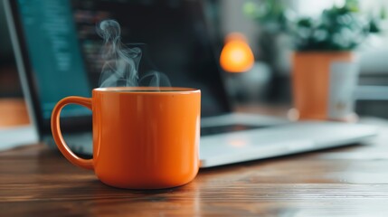 A steaming orange coffee mug on a wooden desk, with a blurred laptop and plant in the background, creating a cozy home office atmosphere. - Powered by Adobe