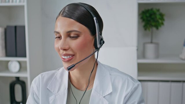 Smiling medic talking headset giving treatment recommendation at clinic closeup.