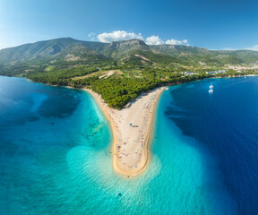 Aerial view of blue sea and Zlatni Rat, Brac island, Croatia in summer. Top drone view of adriatic sea, sandbank, white sandy beach, green trees, mountains, azure water at sunset. Tropical landscape