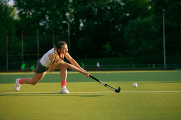 girl hockey player plays field hockey on a sunny day, the hockey player hits the ball with a stick