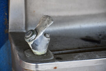 Aluminum drinking fountain stained from wear.