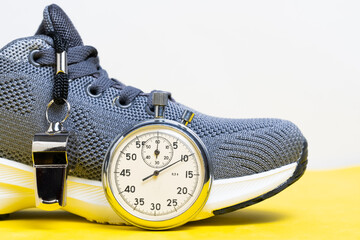 Sports shoes, whistle and stopwatch on yellow background. Sports concept.