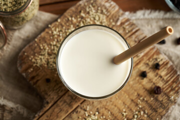 Vegan hemp seed milk in a glass with an ecological bamboo straw, top view