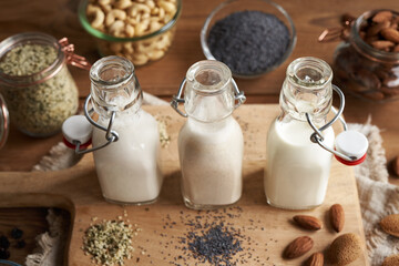 Vegan nut milks made of hemp seeds, poppy seeds and almonds in three glass bottles
