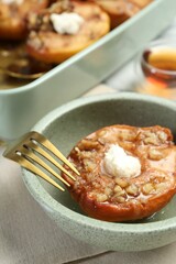 Tasty baked quince with nuts and cream cheese in bowl on table, closeup