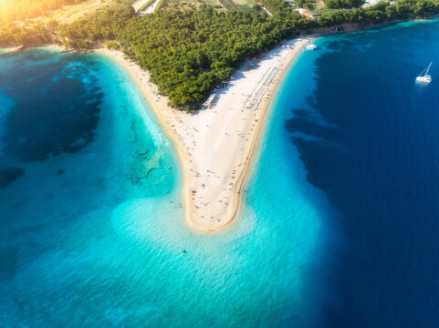 Aerial view of blue sea and Zlatni Rat, Brac island, Croatia in summer. Top drone view of adriatic sea, sandbank, white sandy beach, green trees, azure water at sunset. Tropical landscape. Travel