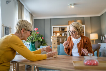 two senior women friends or sisters play leisure board game at home