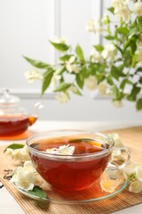 Hot jasmine tea in cup and flowers on white wooden table