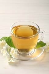 Hot jasmine tea in cup and flowers on white wooden table