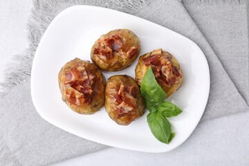 Delicious baked potatoes with bacon and basil on grey table, top view