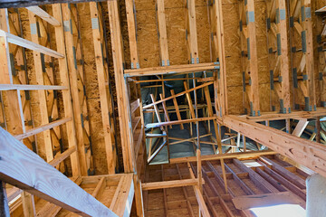 An intricate view of wooden framing in a building under construction, showcasing the detailed structure and craftsmanship involved in modern construction techniques.