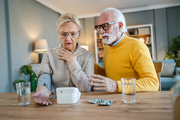 senior couple at home woman check blood pressure husband sit beside