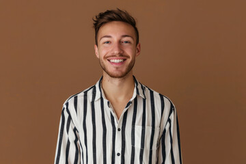 Obraz premium Portrait of nice young man smiling, wearing striped t-shirt isolated on meringue empty background 
