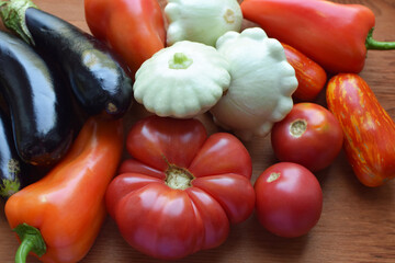 Tomatoes, squash cucumbers, peppers and eggplants on a wooden background. Country natural vegetables.