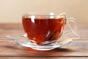 Brewing aromatic tea. Cup with teabag and spoon on wooden table