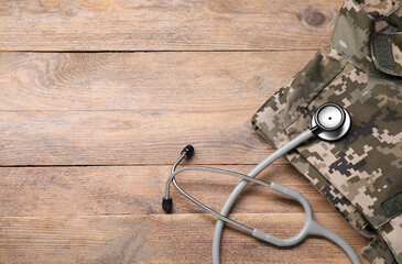 Stethoscope and military uniform on wooden background, above view. Space for text