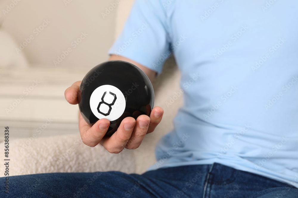 Wall mural Man holding magic eight ball indoors, closeup