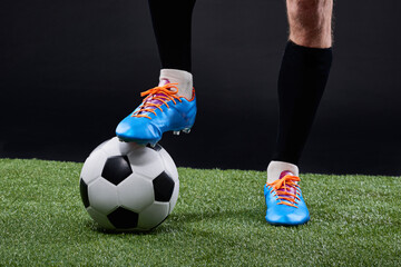 Fototapeta premium Field, soccer player and foot with ball for game, training and action for practice with shoes. Black background, athlete and person with talent for football, outdoor and fitness for sport and goal