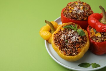 Quinoa stuffed peppers with corn and basil on light green table, closeup. Space for text