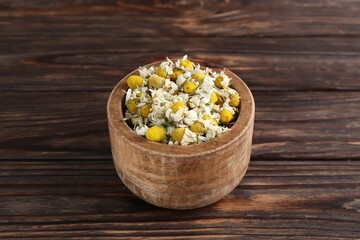Chamomile flowers in bowl on wooden table
