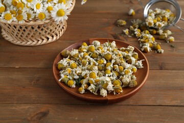 Dry and fresh chamomile flowers on wooden table