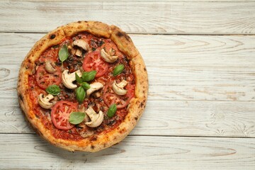 Tasty pizza with basil, mushrooms and tomato on wooden rustic table, top view. Space for text