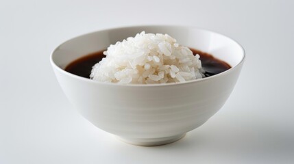 White bowl with glossy coated rice and soy sauce, shallow depth of field 