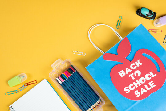 Back to school, apple shaped tag, on paper, shopping bag.  Yellow background.
